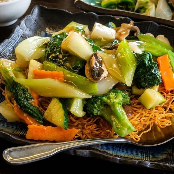 Crispy noodles topped with vibrant stir-fried vegetables, including broccoli, carrots, and bok choy.